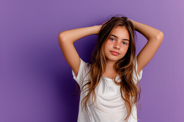 Fototapeta premium Portrait of a serene young girl in a white shirt, touching her hair, set against a vivid purple background, ideal for lifestyle and fashion content
