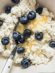 A close-up of cottage cheese with honey and blueberries - is a delicious healthy breakfast