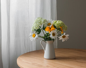 Bouquet of summer garden flowers - hydrangeas, daisies on a wooden table