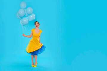 Woman in Yellow Dress Holding Blue Balloons Against Blue Background
