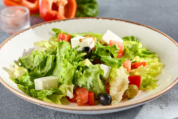 Greek salad with feta cheese and olives on a sunlit textured background