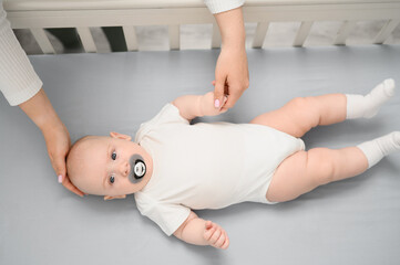 Mom puts baby in crib, creating calming atmosphere in room. Newborn infant is resting peacefully in...