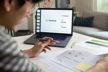 Male Asian graphic designer working in an office studio, designing logos and creating variations of logos, designing logos and showcasing the corporate identity and logo design process.