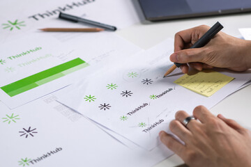 Male Asian graphic designer working in an office studio, designing logos and creating variations of logos, designing logos and showcasing the corporate identity and logo design process.