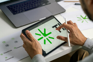 Close-up shot of a graphic designer making notes on logo designs, using a tablet, designing logos,...