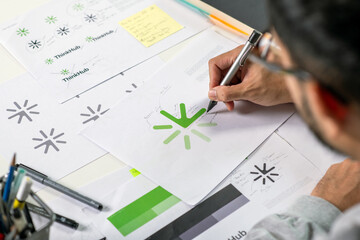 Close-up shot of a graphic designer making notes on logo designs and showcasing the corporate...