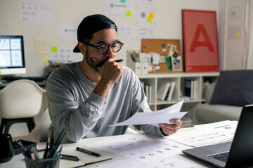Candid shot of Asian graphic designer inspecting logo designs, using computers, designing logos,...