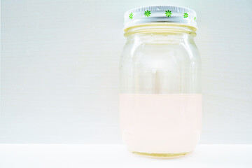 白背景にカレンデュラの花を除いた後の薄ピンク色の自家製の天然花酵母液