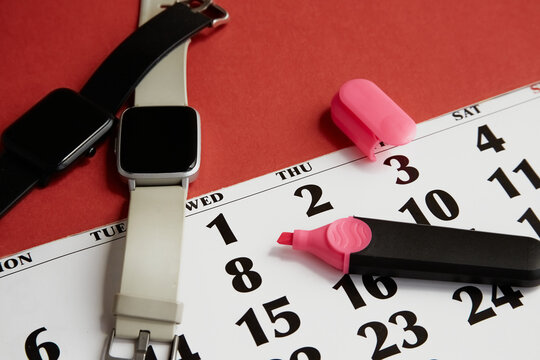 Two fitness tracker side by side and calendar with marker on red background, fitness time, personal records, fitness activities, physical activi