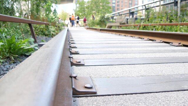 New York City High Line elevated greenway, Manhattan Midtown, USA. People in urban public park. Promenade in garden greenery. American street life, Chelsea highline near Hudson Yards. Railway tracks.