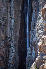 Stream between steep cliffs. Small waterfall in rock, close up. Stream of water, mountain stream flowing. spring melting of glaciers in mountainous areas. 