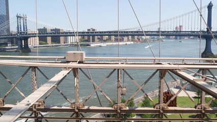 New York City Manhattan Bridge from Brooklyn Bridge. Dumbo carousel, USA travel landmark, NYC skyline cityscape. Iconic architecture thru cables over East River water. Visit United States of America.