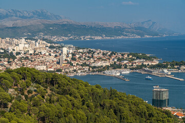 Drone view of the coastal city Split in Croatia with sea view and greenery-covered cliffs