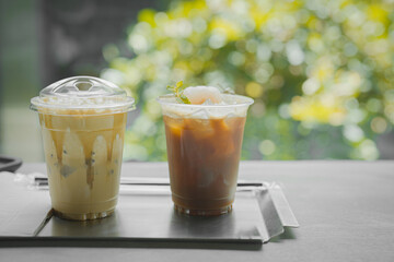 Close up glass of ice black coffee with lychee juice and ice cappucino on raw cement table of a coffee shop summer terrace, menu photography.
