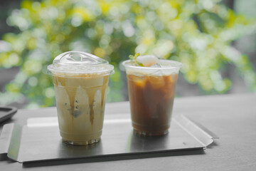 Close up glass of ice black coffee with lychee juice and ice cappucino on raw cement table of a coffee shop summer terrace, menu photography.
