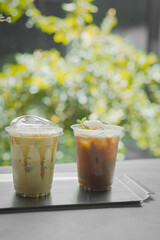 Close up glass of ice black coffee with lychee juice and ice cappucino on raw cement table of a coffee shop summer terrace, menu photography.
