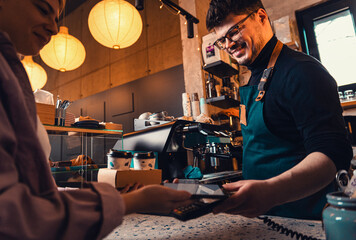 Barista gives takeaway coffee in paper cups to customers in a cafe.