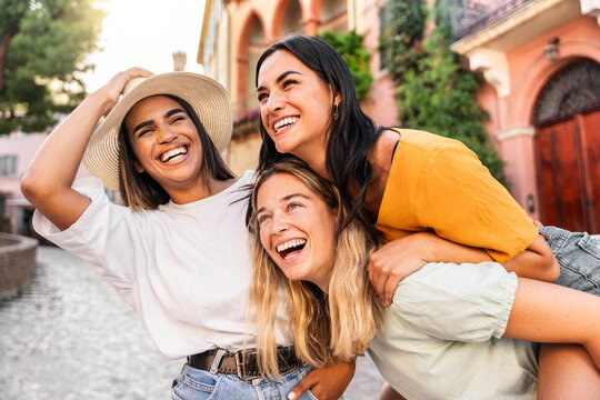 Fototapeta Three multiethnic girls having fun walking in city street - Happy young women laughing together enjoying summertime vacation