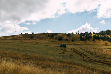 Obraz premium Picturesque countryside scene with a green truck parked on top of a grassy hill in the middle of a field