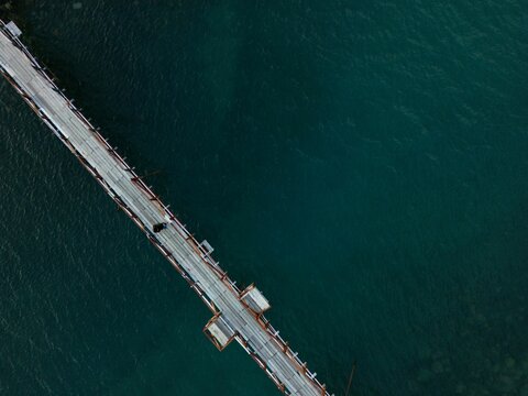 Aerial view of a wooden pier extending into the blue ocean waters