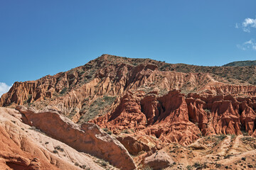 Fairytale canyon with red rocks. Picturesque Skazka Canyon on southern shore of Issyk-Kul lake, Kyrgyzstan. Travel destination, landmark Kirgiziya. Summer natural park landscape