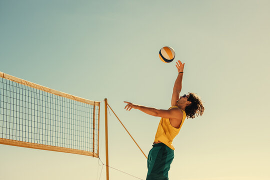 Pro beach volleyball player spiking ball mid air in championship match