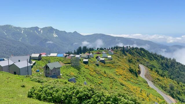 Panoramic aerial view to high mountain village and clouds covering valley. Mountain resort above the clouds. Highland landscape of Gomismta, touristic landmark in the Georgia. 4K