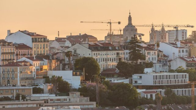Aerial view over the center of Lisbon to the Colorful houses on a hill timelapse during sunset. Dome of Estrela basilica church and working cranes. People on viewpoint. Portugal