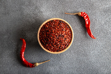 Red pepper flakes.Red chili peppers in wooden bowl on gray background.Dried chili peppers