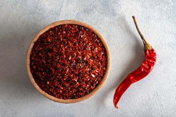 Pepper flakes.Red chili peppers in wooden bowl on light blue background.Dried chili peppers