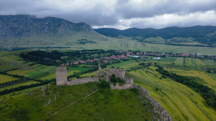 Aerial photo of the ruins of Trascau medieval citadell in Romania. Photography was shoot from a drone with camera level for a panoramic view of the fortification with the mountains in the background.