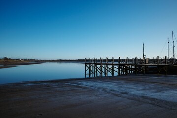 Obraz premium A serene view of a dock extending into a calm body of water under a clear blue sky