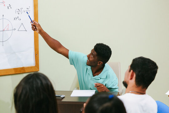 Teacher in the classroom explaining a calculation exercise on the blackboard.