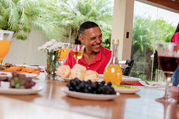 Happy young latin man smiling sitting at table during fun afternoon outdoors.