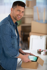 young man unpacking cardboard boxes in new apartment