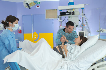 husband and woman giving birth in labor room of hospital