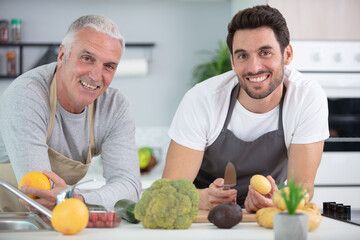 Fototapeta premium two men preparing vegetables for meal at home