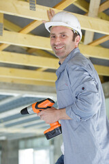 mature builder twists the screw on the ceiling