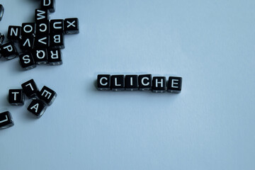 Concept of Cliche written on wooden blocks. Cross processed image on Wooden Background