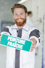 man holding wet paint sign