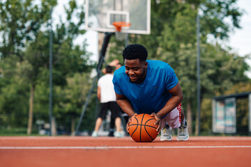 Naklejka premium African american player doing pushups on an basketball outside