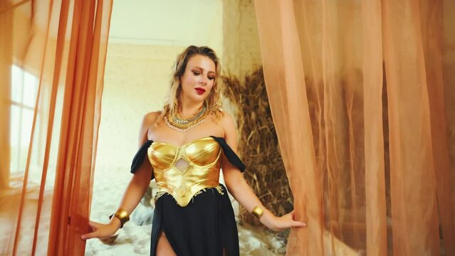 fantasy sexy woman fairy queen posing in desert room full sand. blonde hair beauty face fashion model girl. black dress golden corset gold old style. Lady hand opens curtains silk fabric. art video 4k