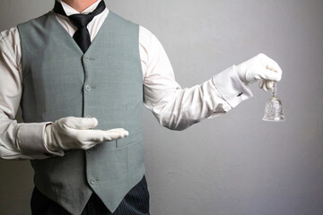 Butler or Hotel Concierge in Waistcoat and White Gloves Holding Glass Bell. Ring for Service....