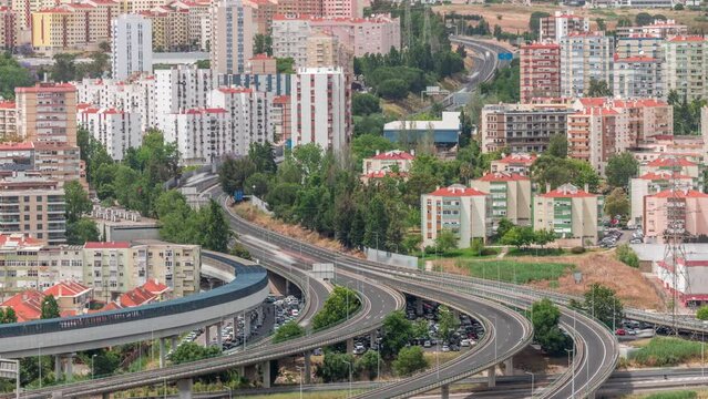 Aerial top view of highway multilevel junction road in urban populated area timelapse. Intersection and overpass with metro train line. Odivelas district in Lisbon, Portugal