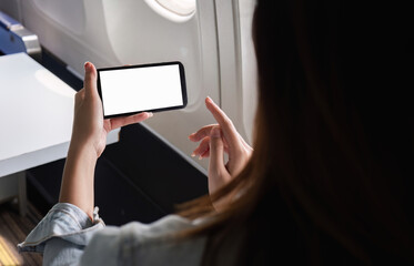 Young Businesswoman Using Smartphone While Traveling by Plane for Work, Focused on Blank Screen, Modern Technology in Business Travel