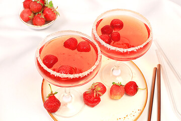Festive alcoholic cocktail, red martini in glasses on a bright background with strawberries, summer bar concept, alcoholic drinks at a party, restaurant and cafe advertising, selective focus.