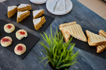 Assorted pastries such as jam tarts and layered desserts beautifully presented on slate trays