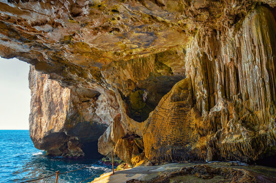Interior of Neptune's Cave with stunning rock formations and a view of the Mediterranean Sea in Capo Caccia, Sardinia. This cave is also known as Neptune's Grotto and Grotta di Nettuno.