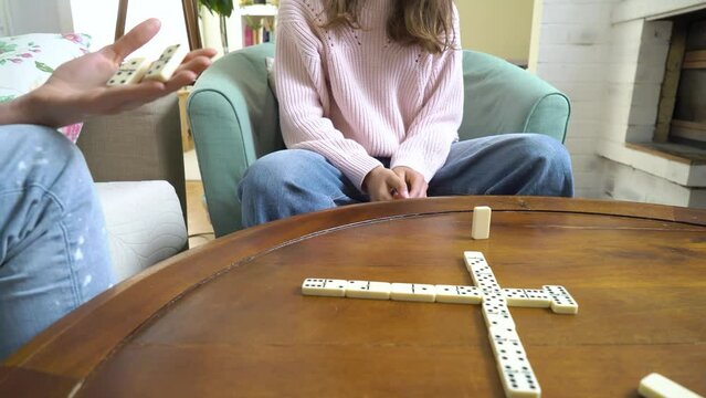 Domino game. Family, young adult woman and her daughter teen girl playing board games in living room