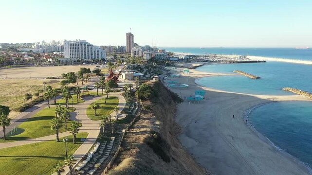 Rear aerial view of buildings in the cityscape, above the coastline, Ashkelon